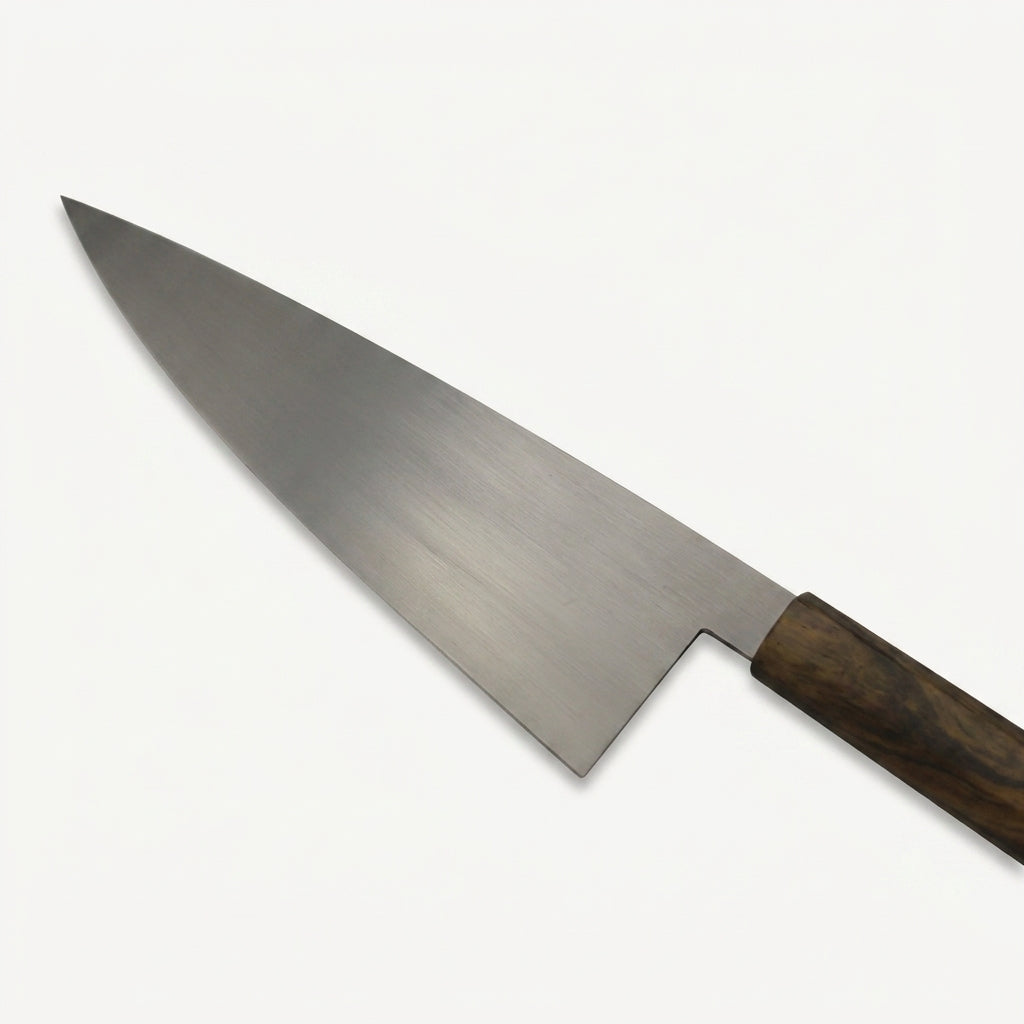 Detail of the HandFab MK-III chef knife blade showing the flat edge profile and fine taper toward the tip